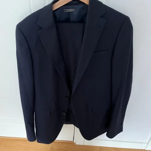 Hel kostym - Mörkblå kostym från Riley i storlek 48, slim fit. Använd någon enstaka gång. Byxor och kavaj.
