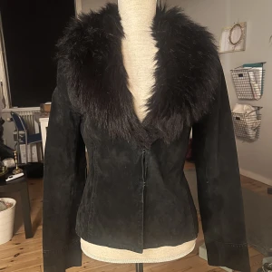 Äkta läder kavaj - Superfin äkta läderkavaj med fakepälskrage. Lite figursydd och kort. Saknar bälte, men inget som syns eller stör. Tycker den passar bättre utan! Står storlek M men jag skulle säga att den är en S då den är liten. 