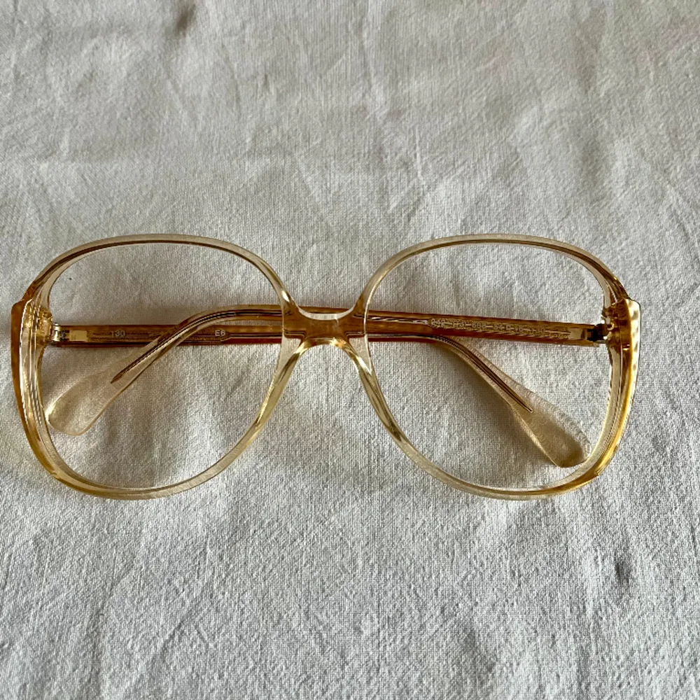 Vintage glasögonbåge från 80 talet  Kommer från en nedlagd Optikbutik, aldrig använd.  Hela bågens bredd 130 mm Glasets storlek, bredd 55 mm, djup 50 mm. Accessoarer.