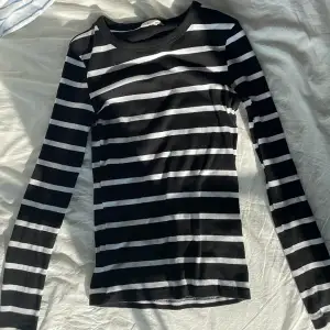 En långärmad tajt, svart och vit randig tröja från Gina Tricot. Storlek S. 