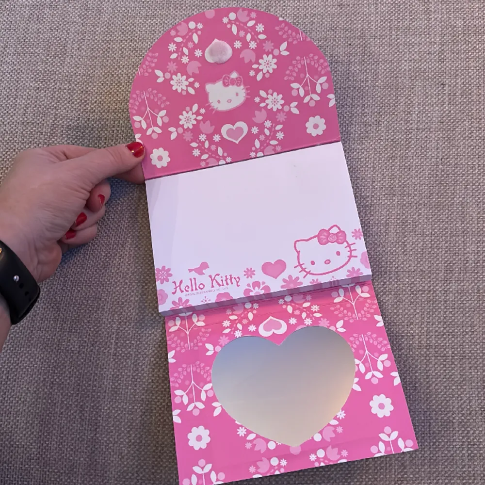 Supergulligt block med Hello Kitty-motiv. Stängs med kardborre. Ej använt block. En hjärtformad spegel på insidan. . Övrigt.