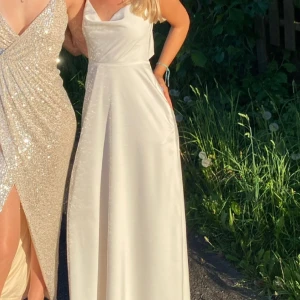 Balklänning i vitt satin tyg  - Så drömmig balklänning från NA-KD som inte längre säljs. Den har dubbelt tyg så den är inte alls genomskinlig och den går ner till fötterna på mig som är 168 cm lång. Skriv för fler bilder och information☺️