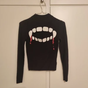 Vampyr tröja - Cool tröja med öppning mellan tänderna. Haft den till halloween ett år o sydde då på fladdermusvingar med knappar men har sprättat upp knapparna. Finns ett litet hål på ryggen. Den är väldigt stretchig. Kan mötas upp i vänersborg