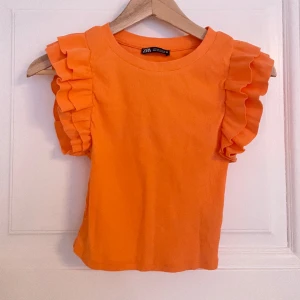 Orange sommar tröja från Zara - Orange topp med volanger på vardera ärm, hyfsat cropad och helt oanvänd!!