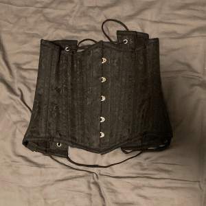 Jättefin Svart korsett med vackert mönster i bra kvalitet från corsets-uk. Köpt second hand men aldrig använd pga att den är för liten.