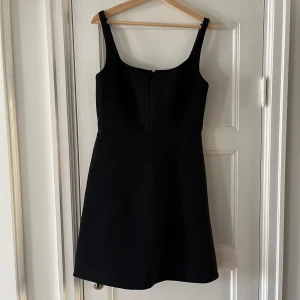 Svart klänning från & Other Stories - En elegant svart klänning från & Other Stories i storlek 40. Klänningen har breda axelband och en dragkedja på baksidan. Den är knälång och har en figurnära passform.