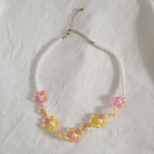 Halsband med blommor - Somrigt halsband med pärlor och blommor. Pärlorna är av plast. Köpt på Monki för flera år sedan. Justerbar kedja💗