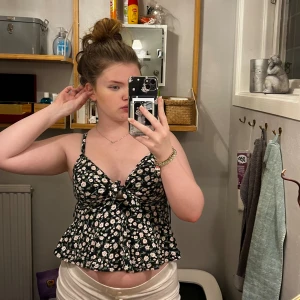 Söt topp - En söt blommig topp! Svart med gröna och rosa o vita detaljer! Volanger Har aldrig använt den därmed inga defekter