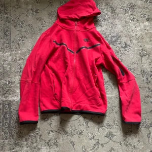 Nike tech - De är en röd Nike tröja som är skön, bra material . Den säljs på grund av att den är för liten ny pris 1000kr jag köpte den ny så den är inte begagnad från innan den är knappt använd 