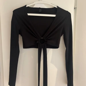 Svart fest-topp - Storlek XS Sparsamt använd topp med knytning som man snörar runt magen.  Väldigt, väldigt snygg men tyvärr är detta inte min stil längre.