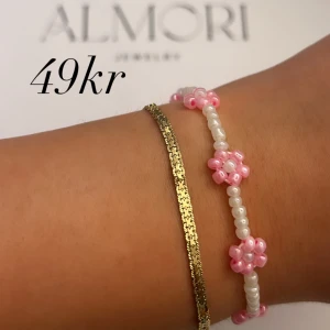 Två armband från Almori - Ett armband från Almori. Handgjort pärlarmband med vita och rosa pärlor formade som blommor.