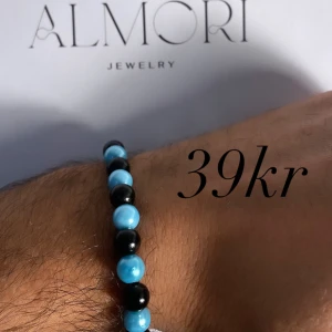 Armband från Almori - Ett stilrent armband från Almori med svarta och blå pärlor. Armbandet är elastiskt och passar de flesta handleder.