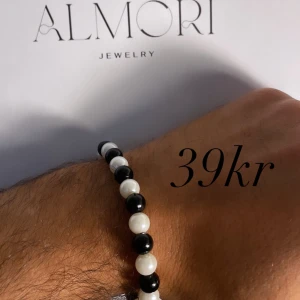 Armband från Almori - Ett elegant armband från Almori med svarta och vita pärlor. Armbandet är elastiskt och passar de flesta handleder.