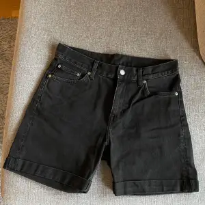 Svarta jeanshorts med fickor fram och bak. Shortsen har en knapp och dragkedja i midjan.  Mycket fin denimshorts i nyskick. Använd max.2 gånger. Hel och ren.  Köpte för 500 kr. Kommer från rökfritt och djurfritt hem.