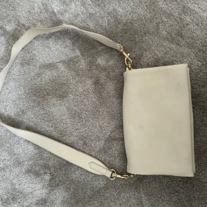 Vit axelbandsväska - Säljer min vita axelbandsväska från NA-KD då jag inte använder den längre. Köpt för 699
