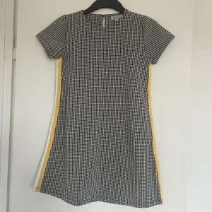 Klänning  - En fin klänning som går att ha till alla möjliga tillfällen. Den sitter lite tight runt midjan om man gillar sånt. Har ett jätte fint och modernt mönster med en guld rad på sidan. Har ett jätte skönt material. 