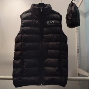 EA7 väst - Jag säljer min EA7 väst. Man får med en påse som man kan förvara västen i. Nypris ca 1200 kr. Storlek 160 cm. 14 år.