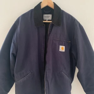 Carhartt OG Detroit jacket  - Säljer en svin najs carhartt jacka. Jackan har inga defekter eller fel, utan endast små tecken på att den är använd lite över hela jackan(se bild 5). Jackan är i mörkblå färg och är sparsamt använd, hör av er vid intresse! 
