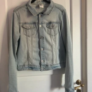 Ljusblå jeansjacka från H&M - Säljer en snygg ljusblå jeansjacka från H&M i storlek M. Jackan är i bra skick och passar till många olika outfits. Perfekt för vår och sommar.