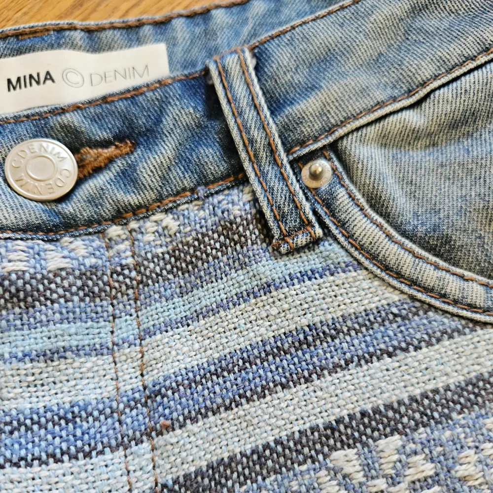 Ett par jeansshorts från MINA Denim med ett randigt mönster på framsidan. . Shorts.