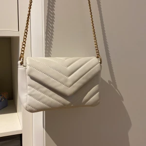 Vit handväska 🤍🤍 - En vit fin handväska med guld kedja (inte riktigt guld) som är använd men i bra skick! Den har några små fläckar som inte syns långt ifrån!💋💋💋