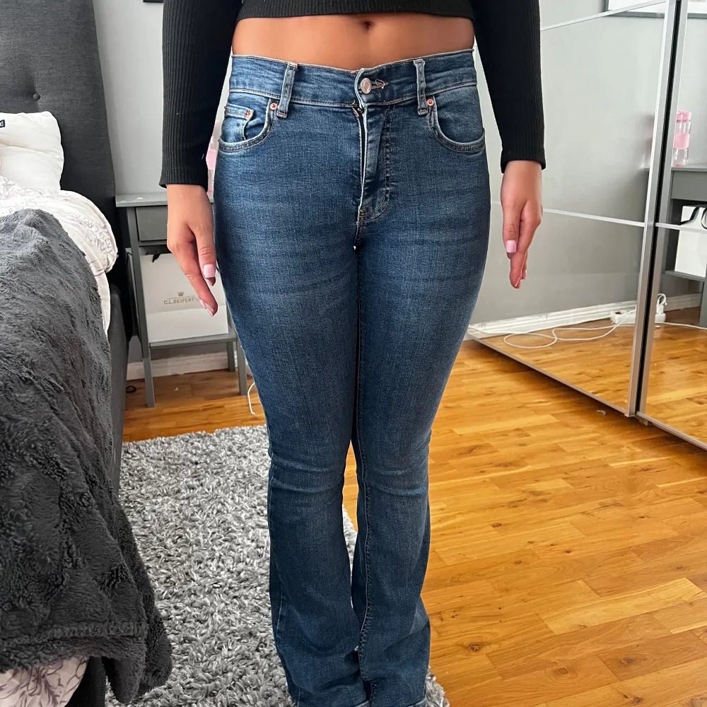 Mörkblåa jeans från ginatricot i modellen low waist bootcut jeans, dock mer åt mid waist hållet. Jeansen är i storlek 34 och är vi väldigt bra  skick förutom ett litet hål vid slutet av ens benet. Hon på bilderna är 166cm. (Orginalpris 499kr). Jeans & Byxor.