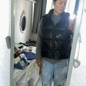 Svart dunväst från Shein - Säljer en svart dunväst från Shein i storlek M. Västen är perfekt för höst och vinter, med en dragkedja framtill och en hög krage för extra värme. Den är i nyskick och har en glansig yta som ger en snygg look. Passar bra till både vardag och fest!