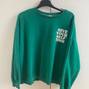 Grön tjocktröja - Grön tjocktröja med ” give yourself time” på framsidan och baksidan. Skön material och bra i storlek. Tycker den inte är min smak längre så ska sälja den. 