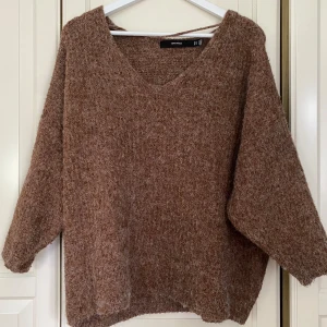 Brun stickad tröja från Vero Moda - Säljer en supermysig brun stickad tröja från Vero Moda. Den har en avslappnad passform och är perfekt för höst och vinter. Tröjan har en v-ringad hals och långa ärmar. Perfekt för att hålla sig varm och snygg under de kallare månaderna! 🧡