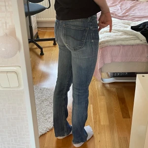 Blå jeans från Lee - Ett par blå jeans från Lee i modellen 'Bonnie'. Jeansen har en bootcut-stil och är tillverkade av 98% bomull och 2% elastan, vilket ger dem en bekväm passform. De har en klassisk femficksdesign och stängs med dragkedja och knapp.