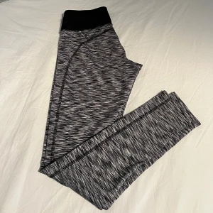 Grå och svarta leggings från SOC - Ett par grå och svarta leggings från SOC med ett mönster i grått och svart. Leggingsen har en hög midja och är tillverkade i ett stretchigt material som passar bra för träning.