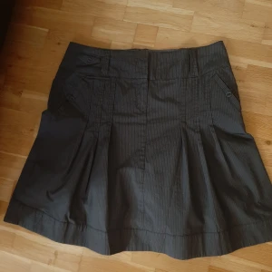 Randig kjol  - Grårandig veckad kjol. Kjolen är i ett mycket bra skick och har inga märkbara skavanker. Den är något mellanting mellan midi och minikjol 