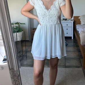 Vit klänning - Vit klänning i storlek 34 från Nelly. Finns en mindre fläck på kragen, se bild 4. Vissa diamanter sitter lite löst men jag tycker inte det märks när man har på sig den. 