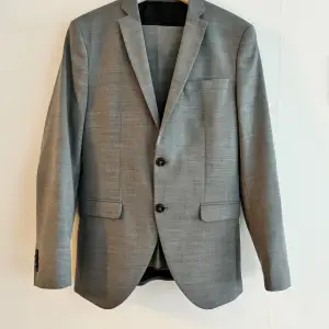 Säljer en snygg grå kostym från Jack & Jones Premium, kavaj med byxor.  Premium i super slim. Kavaj i storlek 46 , byxor i storlek 44. Använd två gånger. Skickar snabbt inför din student. 