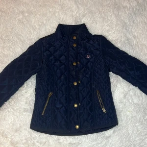 Svart väst. - Svart väst med rosa text.