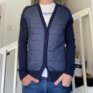 Merino Cardigan - Säljer nu en fet Cardigan från Peak Performance, perfekt till vår eller sena sommarkvällar. Den stickade delen är i 100% Merinoull. Skicket är 7/10 endast två små hål✅