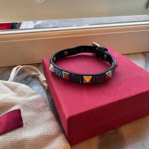 Svart armband med nitar - Valentino Armband limited edition. kostar ~4000kr nytt, har endast kvar box, alla paljetter är kvar. Vill ha runt 2000kr men lyssnar på bud!🌟