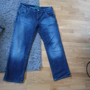 Mörkblåa jeans - Jeans med najs fade och coola detaljer. De är i bra skicka med lite slitna längst ner.