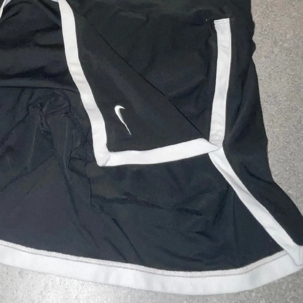 Svart tenniskjol från Nike med vita detaljer, integrerade shorts på insidan, storlek XS 🫶🏼. Kjolar.