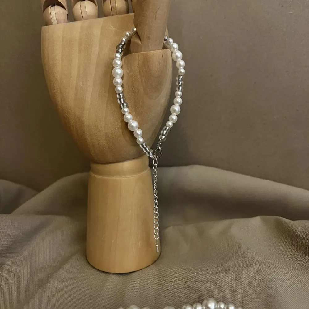 Armbandet Izabelle består av olika storlekar av vita pärlor med silvriga små pärlor. Låset och kedjan är i silver.  Namn: Izabelle Längd: Hela 23 cm Pärlor 15,5 cm Pris: 99 kr. Accessoarer.