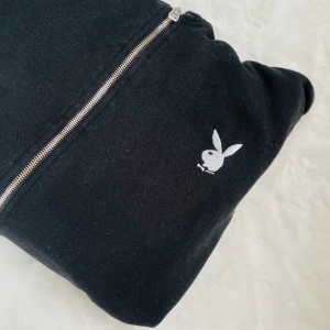 Playboy ziptröja - Säljer en svart Playboy luvtröja med zip. Finns tryck både på ena ärmen och på ryggen. Använd fåtal gånger så i fint skick. Köpt på Missguided x Playboy. Säljer billigt istället för att den slängs👄