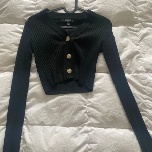 Svart långarmad - Kort långarmad svart tröja med knappar. Tröjan är från missguided. Passar till xs/s
