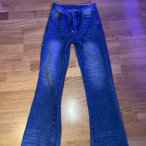 Blå jeansbyxor - Ett par blå jeansbyxor med en lätt utsvängd bootcut-stil. Byxorna har en klassisk femficksdesign och en broderad detalj på bakfickan.