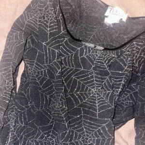 Festtopp med spindelnät - Perfekt festtopp till halloween. Tunn i tyget och långärmad. Storlek s