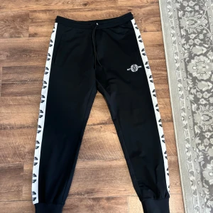 Better Bodies Bronx Track Pants V2 - Better Bodies Bronx Track Pants V2 Herrbyxor. Dom är som nya,, endast använd 1 gång. Säljes då det blev fel storlek.  Snygga svarta träningsbyxor med vita detaljer. Byxorna har en bekväm passform. Storlek M