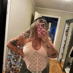 Rosa spetslinne - Ett vackert rosa spetslinne med tunna axelband och en delikat spetsdesign. Linnet har en lätt och luftig känsla, perfekt för varma dagar. halterneck. endast provad. Storlek 3XL