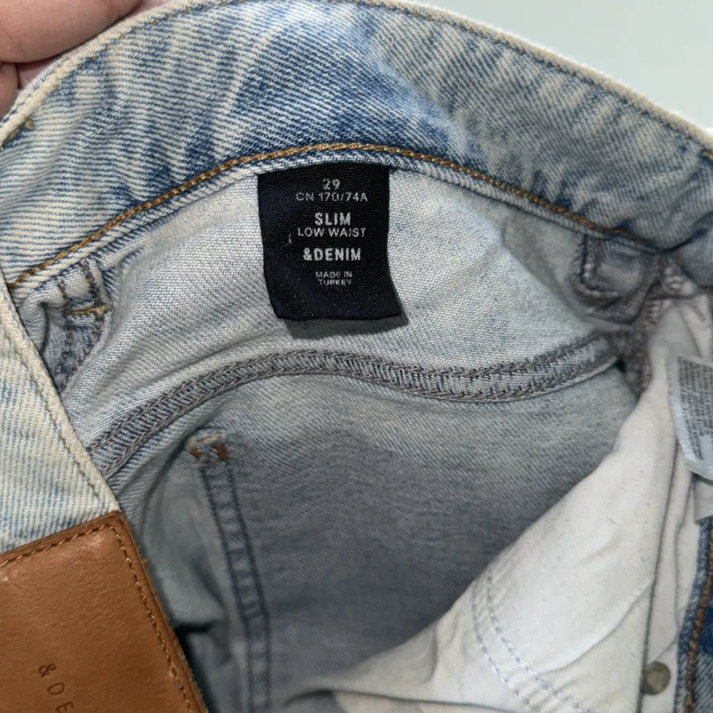 Ett par ljusblå jeans från &Denim med en broderad ros på framsidan och baksidan. Jeansen har en klassisk femficksdesign och är tillverkade i denimtyg. NYPRIS 1800kr. Jeans & Byxor.