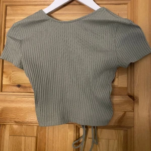 Grön topp - Grön topp från Zara med öppen rygg och snören. Kommer ej till användning och har använt ett fåtal gånger!
