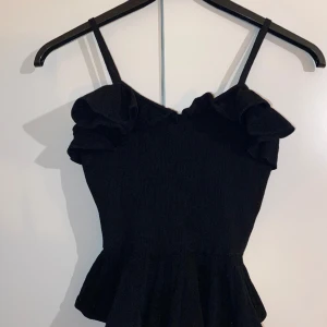Svart elegant linne  - Peplum och frills, svart jersey topp.