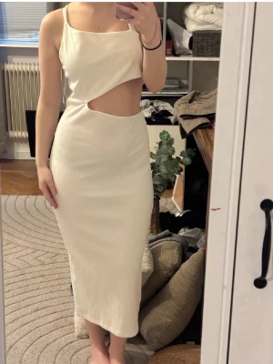 Sommarklänning❤️ - Trendig vit långklänning i ribbat material med smala axelband och snygg cut out-detalj vid midjan. Klänningen har en kroppsnära passform och är perfekt för dig som vill sticka ut med en modern look.